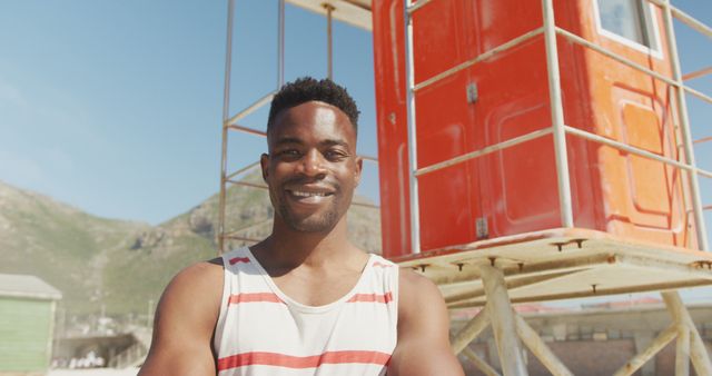 Smiling Man Posed In Front Of Colorful Lifeguard Tower at Beach - Download Free Stock Images Pikwizard.com