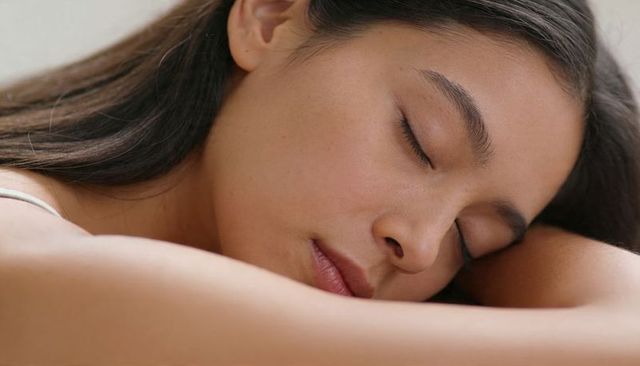 Closeup peaceful young woman sleeping on folded forearm portrait showing calm expression