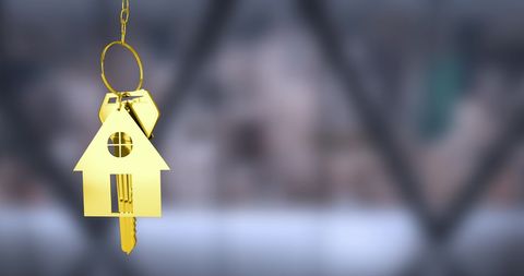 Golden house keychain hanging against blurred backdrop