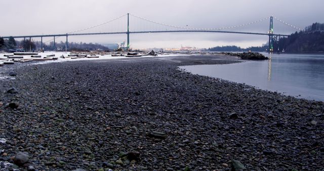 Overcast Day by Coastal Pebble Beach with Suspension Bridge in Background - Download Free Stock Images Pikwizard.com