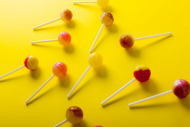 Overhead view of sweet lollipops scattered against yellow background - Download Free Stock Photos Pikwizard.com