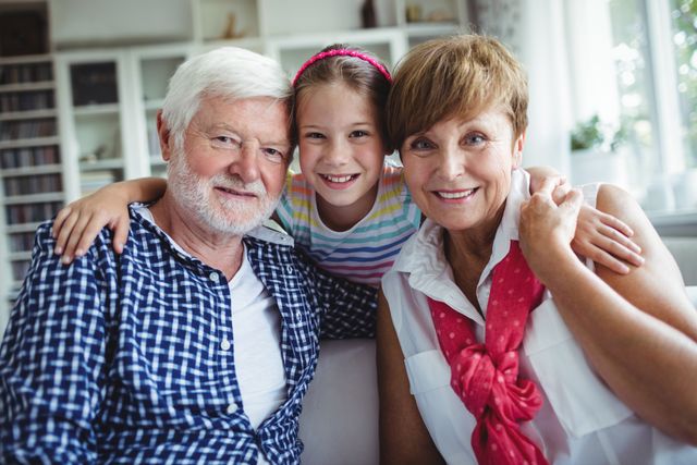 Portrait of smiling grandparents with her grand daughter at home