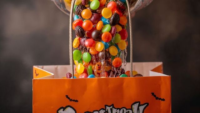 Vibrant Halloween Treats Pouring into Orange Bag