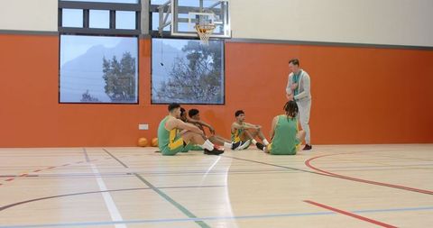 Diverse Basketball Team Listening to Coach in Gymnasium Session