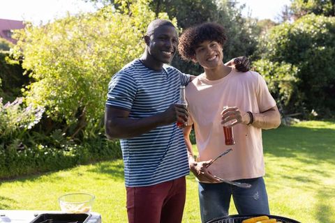 Male Friends Enjoy Grilling Together in Sunlit Garden
