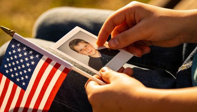 Holding polaroid portrait with american flag on denim lap during golden hour