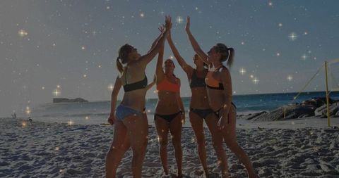 Friends celebrating on beach group high-five during golden hour with ocean backdrop