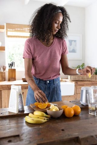 African american woman preparing fresh fruit in bright rustic kitchen for healthy living