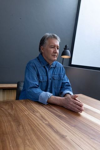 Mature man in relaxed denim shirt planning in modern workspace