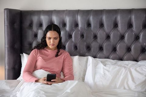 Woman Relaxing in Bedroom Using Smartphone