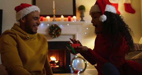 Joyful Couple Celebrating Christmas by Fireplace with Gifts