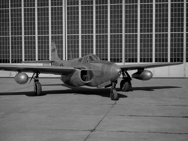 A Bell P-59B Airacomet sits beside the hangar at the National Advisory Committee for Aeronautics (NACA) Lewis Flight Propulsion Laboratory. In 1942 the Bell XP-59A Airacomet became the first jet aircraft in the US. The Airacomet incorporated centrifugal turbojet engines that were based on British plans secretly brought to the US in 1941. A Bell test pilot flew the XP-59A for the first time at Muroc Lake, California in October 1942. The General Electric I-16 engines proved to be problematic. In an effort to increase the engine performance, an Airacomet was secretly brought to Cleveland in early 1944 for testing in the Altitude Wind Tunnel. A series of tunnel investigations in February and March resulted in a 25-percent increase in the I-16 engine’s performance. Nonetheless, Bell’s 66 Airacomets never made it into combat.    A second, slightly improved Airacomet, a P-59B, was transferred to NACA Lewis just after the war in September 1945. The P-59B was used over the next three years to study general jet thrust performance and thrust augmentation devices such as afterburners and water/alcohol injection. The P-59B flights determined the proper alcohol and water mixture and injection rate to produce a 21-percent increase in thrust. Since the extra boost would be most useful for takeoffs, a series of ground-based tests with the aircraft ensued. It was determined that the runway length for takeoffs could be reduced by as much as 15 percent. The P-59B used for the tests is now on display at the Air Force Museum at Wright Patterson.