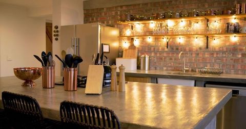 Rustic industrial kitchen showcasing concrete countertop, copper utensils, shelf lights