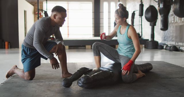 Female MMA fighter training with her coach on gym floor. Perfect for articles and advertisements related to fitness, martial arts, women's empowerment, and sports training.