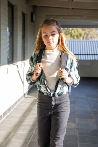 Confident Schoolgirl Walking Through Sunny School Corridor
