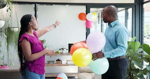 Colleagues preparing office for celebration with colorful balloons