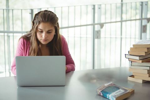 Focused student using laptop in bright library for study