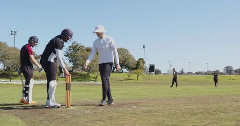 Dynamic Cricket Players Running Between Wickets on Sports Field
