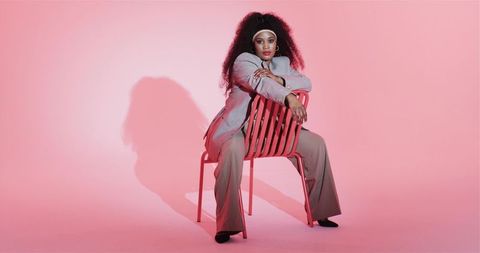 Confident Woman in Stylish Suit Posing on Red Chair