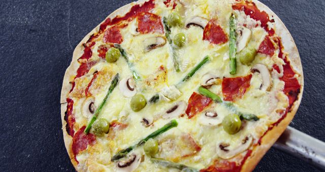 Delicious homemade pizza topped with pepperoni, green olives, asparagus, mushrooms, and melted cheese. Ideal for illustrating Italian cuisine, menu designs, food blogs, and restaurant marketing materials.