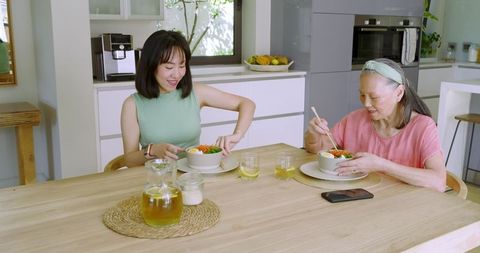 Chinese Mother and Daughter Enjoying Meal Together in Kitchen