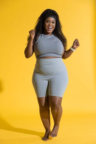 Empowered plus-size african american woman celebrating in gray athleisure on bright yellow