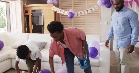 African american family decorating home for birthday party with purple balloons and banner