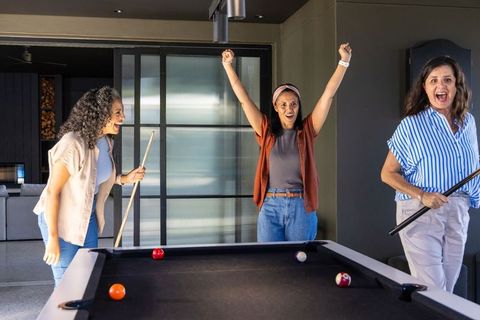 Trio of women cheering winning pool shot in contemporary lounge