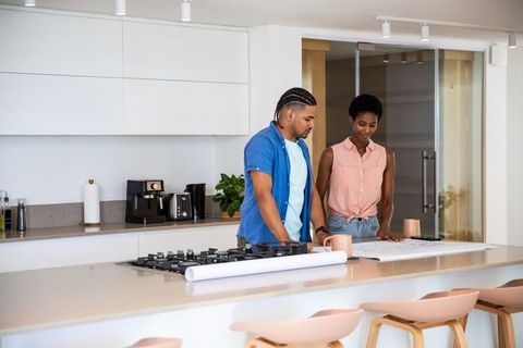 Couple Reviewing Blueprints in Modern Kitchen Renovation Scene