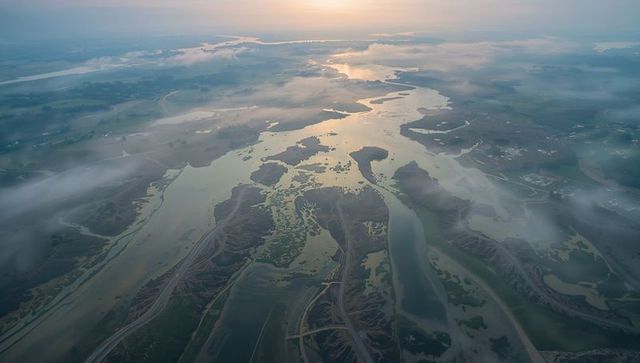 Sunrise over braided estuary and tidal marshes with morning mist and winding channels
