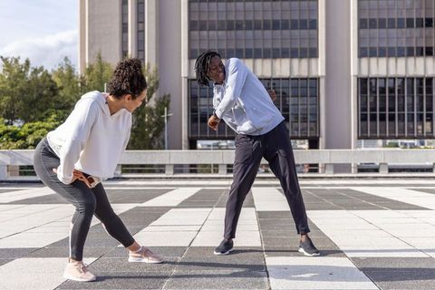 Diverse friends stretching and lunging on urban rooftop terrace during outdoor workout