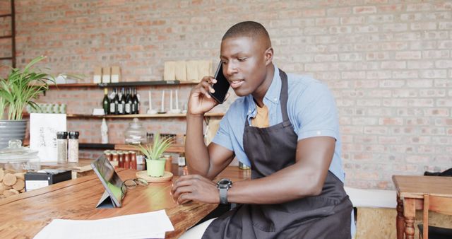 Young male café owner on phone while multitasking with digital tablet - Download Free Stock Images Pikwizard.com