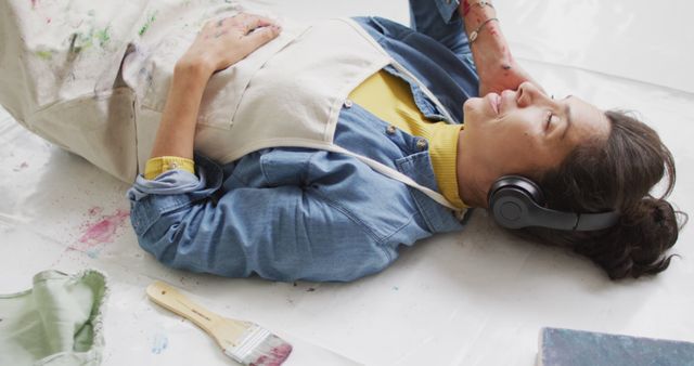 Artist Resting on Floor with Paint-Splattered Clothes and Brushes - Download Free Stock Images Pikwizard.com