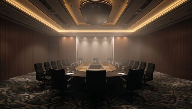 Executive oval boardroom with leather swivel chairs, cove lighting and wood-paneled walls