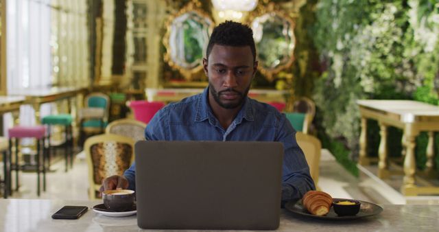 Focused Man Working on Laptop in Trendy Cafe with Coffee and Croissant - Download Free Stock Images Pikwizard.com