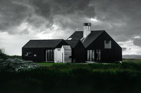 Black Coastal Modern House Under Dramatic Storm Clouds