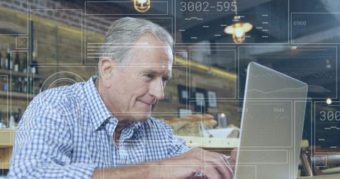 Senior man engaged in technology using laptop at coffee shop