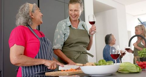 Senior Friends Cooking and Socializing in Kitchen with Wine