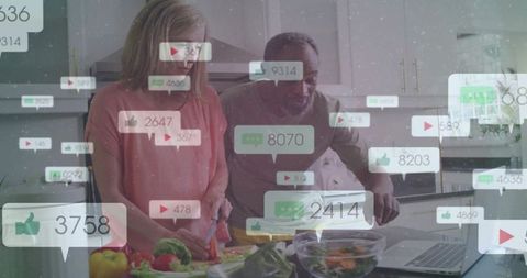 Older couple cooking and chopping vegetables while receiving social media notifications