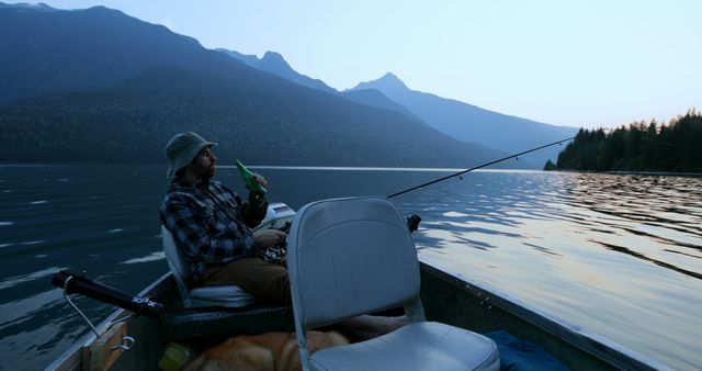 A middle-aged Caucasian man enjoys fishing from a boat on a serene lake at dusk, with copy space. His relaxed posture and the tranquil surroundings suggest a peaceful retreat into nature.