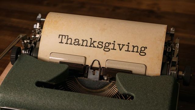 Vintage green typewriter typing thanksgiving on aged paper