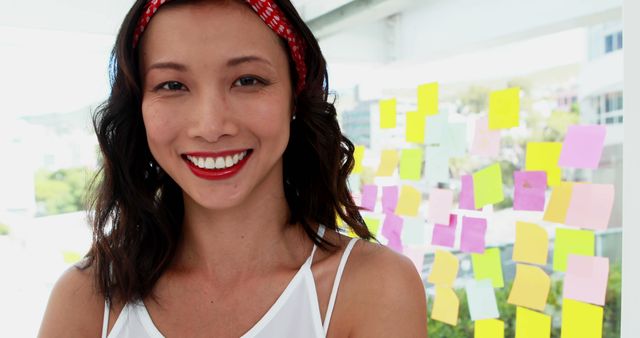 Confident Woman with Sticky Notes in Background Smiling During Work Session - Download Free Stock Images Pikwizard.com