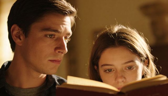 Man and teen girl reading hardcover book together at home studying and focusing