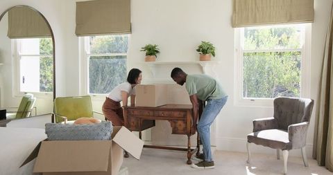 Joyful couple unpacking boxes in new home living room