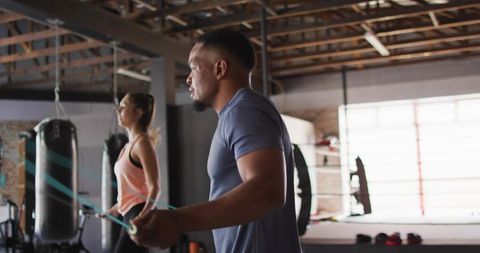 High-intensity jump rope training duo in industrial boxing gym with heavy bags