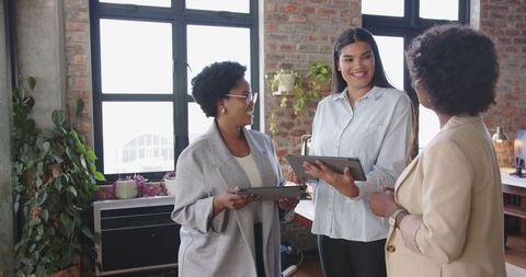 Diverse Female Team Discussing Work with Technology in Modern Office