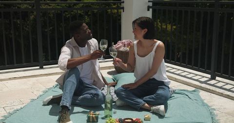 Couple Enjoying Outdoor Picnic Sharing Wine and Snacks in Sun