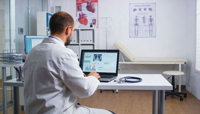 Doctor reviewing chest x-ray and patient data on laptop in modern clinic