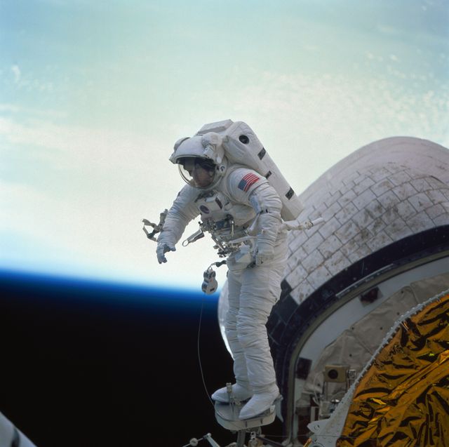 Astronaut James H. Newman is seen conducting an evaluation of the Portable Foot Restraint during an Extravehicular Activity (EVA) outside the Space Shuttle Discovery. This activity was carried out in preparation for the Hubble Space Telescope servicing mission. Both Newman and Carl E. Walz participated in this long EVA, important for future operations in space. This iconic scene can be used in educational materials, highlighting advancements in space technology and the efforts of NASA's astronauts, or in any context celebrating achievements in space exploration.
