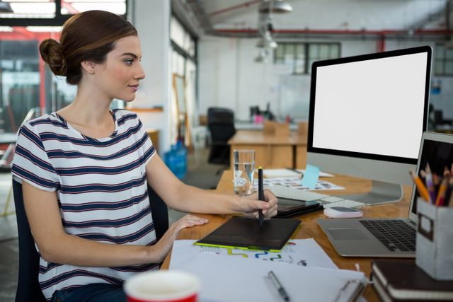 Graphic designer using graphic tablet and desktop in creative office